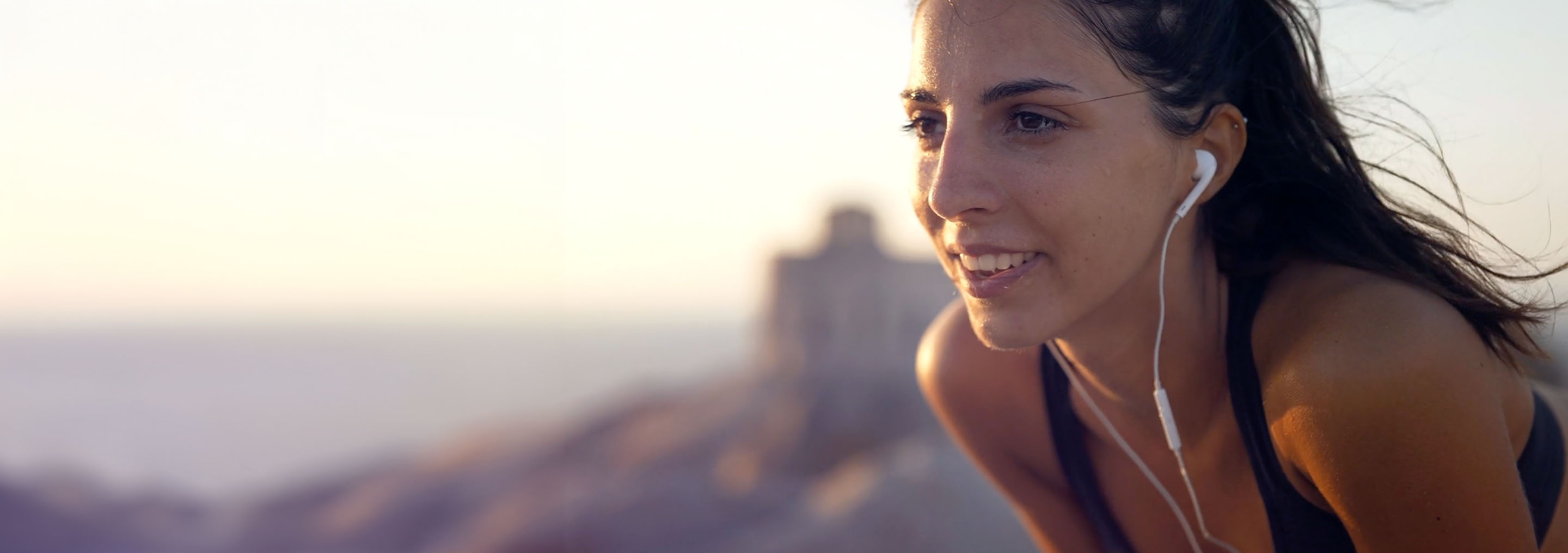Mujer corriendo al aire libre con auriculares, disfrutando de un momento de ejercicio y bienestar.