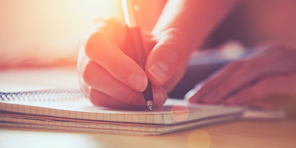 Mano de una chica con un lapicero escribiendo ideas en una libreta Mano de una chica con un lapicero escribiendo ideas en una libreta