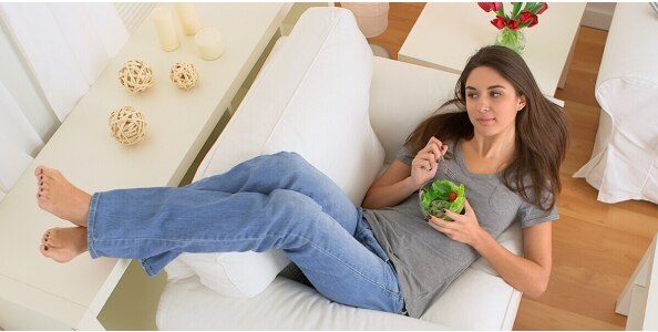 Mujer acostada en un mueble y comiendo